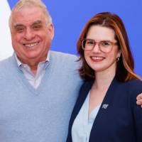 Laura Aikens poses for a photo with an alum in front of the GVSU background
